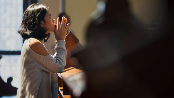 Stylish woman praying at a church and wearing modern Christian jewelry from Glor-e