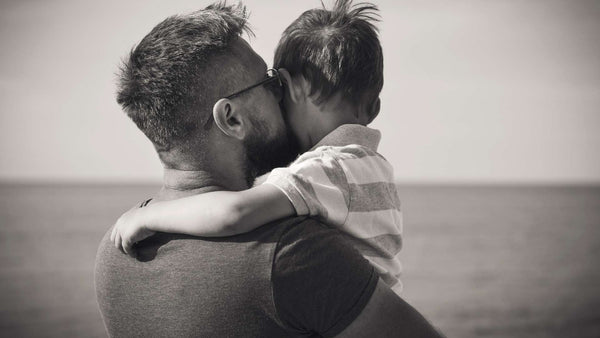 A father kissing his son on the left cheek