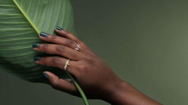 Black female hand holding a leaf and wearing modern Christian rings from Glor-e