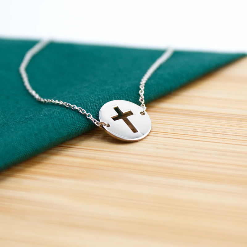 Silver Christian bracelet with a cross charm on a wooden surface | Glor-e