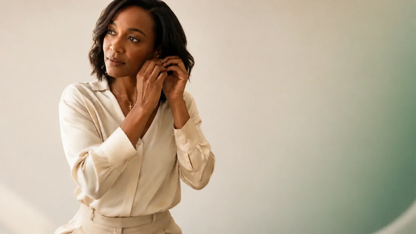 Woman wearing Glor-e's LINKED gold cross necklace against a refined studio background
