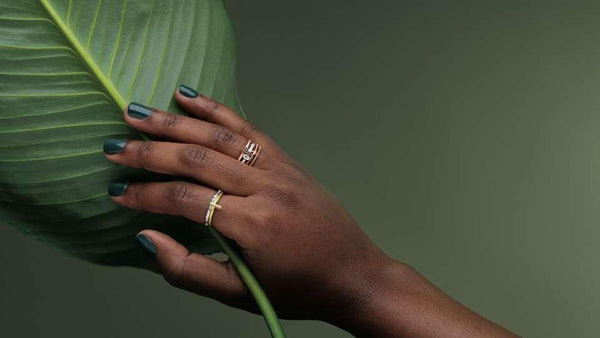 Black female hand holding a leaf and wearing Christian rings from Glor-e