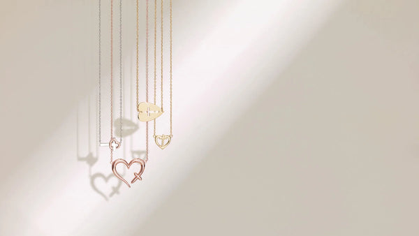 Three gold Christian necklaces with heart pendants – styled on a light beige background